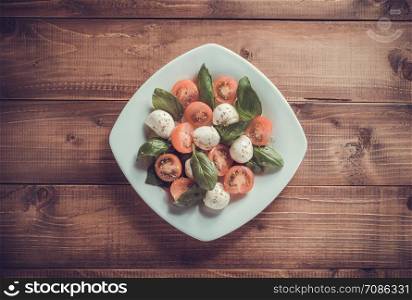 caprese salad in plate at wooden background
