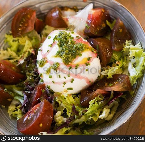 Caprese salad with burrata mozarella, tomatoes and pesto sauce