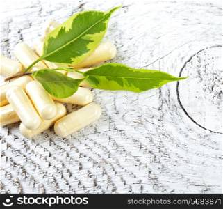 Capsules on white wooden background.