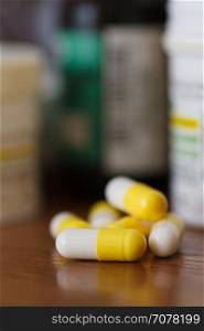Capsules with medicines. Yellow-white capsules with medications on the bedside table, close-up