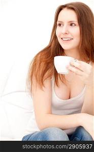 Captivating woman holding a cup sitting on a sofa at home