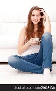 Captivating woman holding a cup sitting on the floor at home