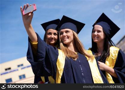 Capturing a happy moment.Students group college graduates in graduation gowns and making selfie photo