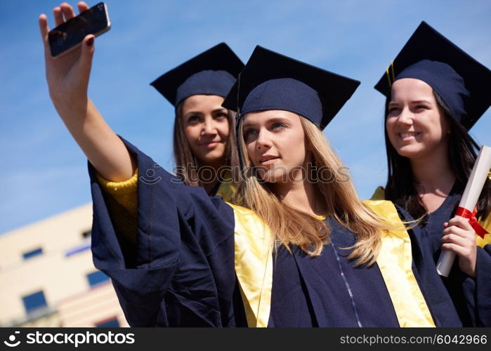 Capturing a happy moment.Students group college graduates in graduation gowns and making selfie photo