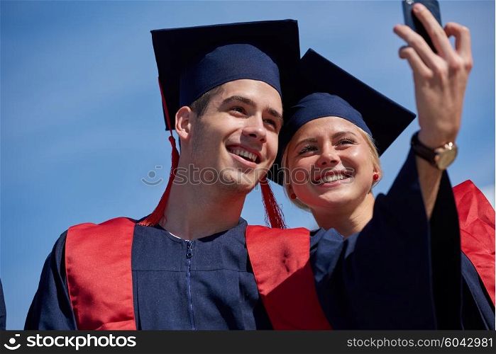 Capturing a happy moment.Students group college graduates in graduation gowns and making selfie photo