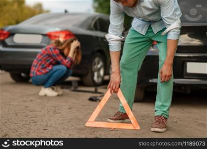 Car accident on road, male and female drivers. Automobile crash, emergency stop sign. Broken automobile or damaged vehicle, auto collision on highway. Car accident on road, male and female drivers