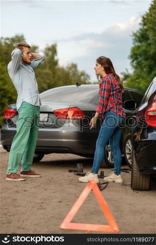 Car accident on road, man and woman are sorted out. Automobile crash, emergency stop sign. Broken automobile or damaged vehicle, auto collision on highway