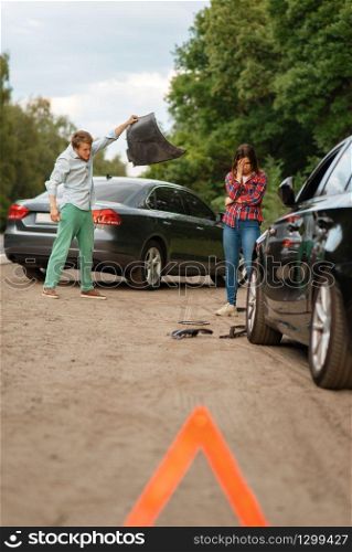 Car accident on road, man and woman are sorted out. Automobile crash, emergency stop sign. Broken automobile or damaged vehicle, auto collision on highway. Car accident on road, man and woman are sorted out