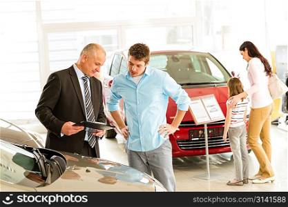 Car agent showing vehicle to young family