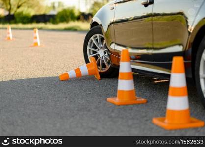 Car and downed traffic cone, lesson in driving school concept, nobody. Teaching to drive vehicle theme. Driver&rsquo;s license education. Car and downed cone, driving school concept