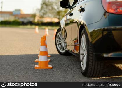 Car and orange traffic cones, lesson in driving school concept, nobody. Teaching to drive vehicle theme. Driver&rsquo;s license education. Car and traffic cones, driving school concept