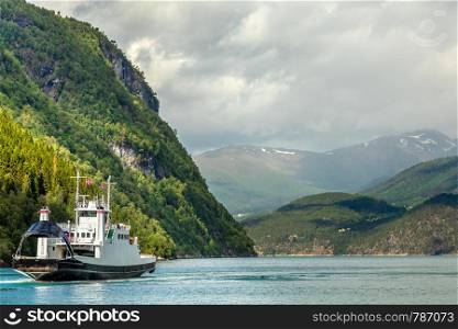 Car and passenger ferry crossing the fjord with mountain landscape in the background, Tafjord, More og Romsdal county, Norway.Norway