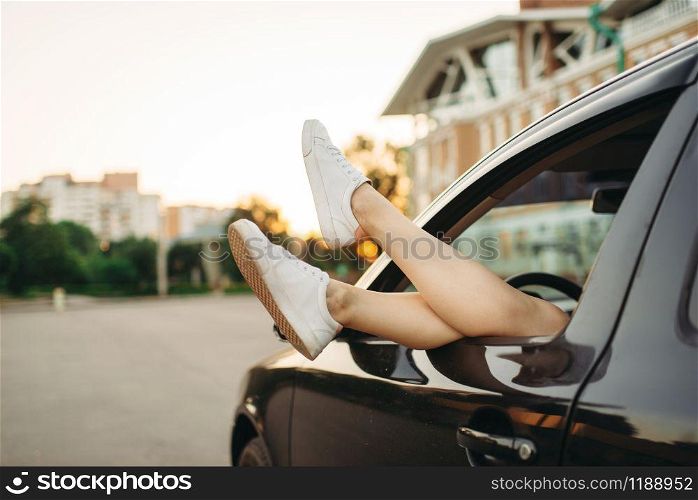 Car breakdown concept, female legs sticking out the window on the roadside. Woman driver waiting for emergency service, broken vehicle. Car breakdown, female legs sticking out the window