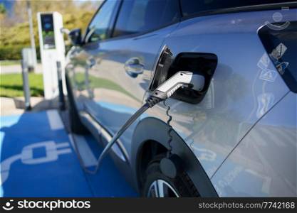Car charging its electric battery at one charging point for electric vehicles located on the street.. Refueling an electric car, an environment friendly alternative