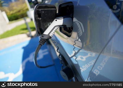 Car charging its electric battery at one charging point for electric vehicles located on the street.. Refueling an electric car, an environment friendly alternative