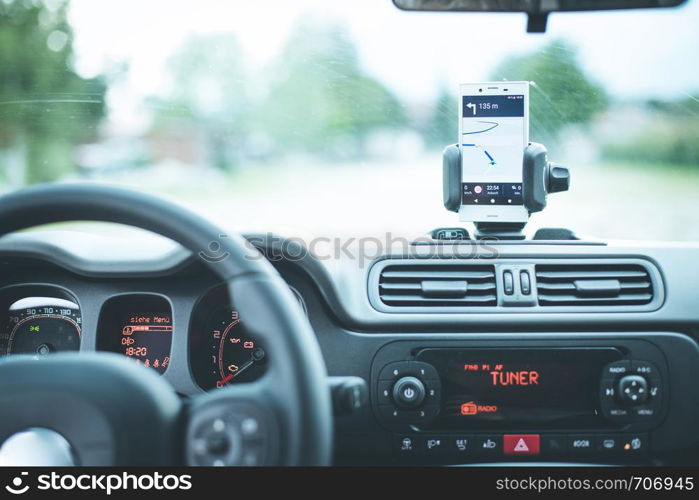 Car dashboard with smartphone used as navigation device, bright and sunny day