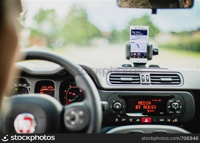 Car dashboard with smartphone used as navigation device, bright and sunny day
