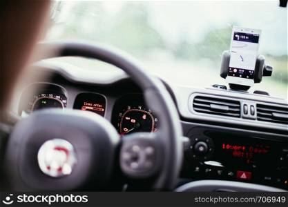 Car dashboard with smartphone used as navigation device, bright and sunny day