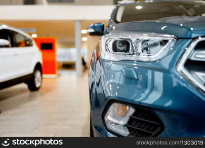 Car dealership, closeup view on automobile headlight, nobody. New vehicle showroom, auto dealer business concept. Car dealership, closeup view on vehicle headlight