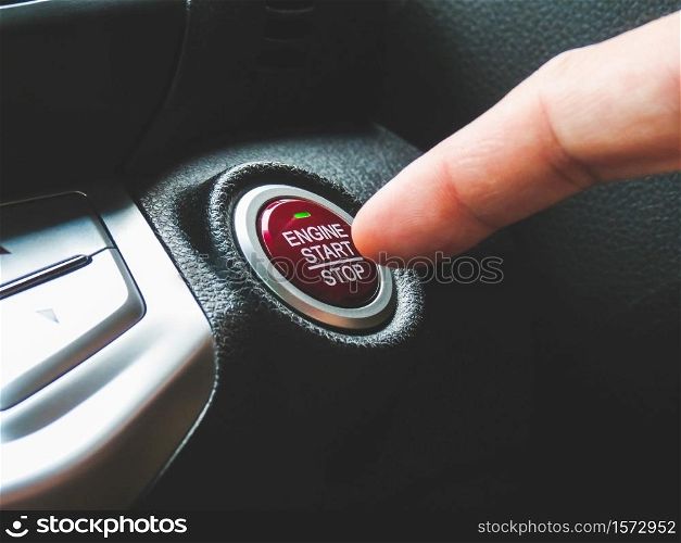 Car driver press to the engine start stop button for engine ignition in a luxury car