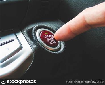 Car driver press to the engine start stop button for engine ignition in a luxury car