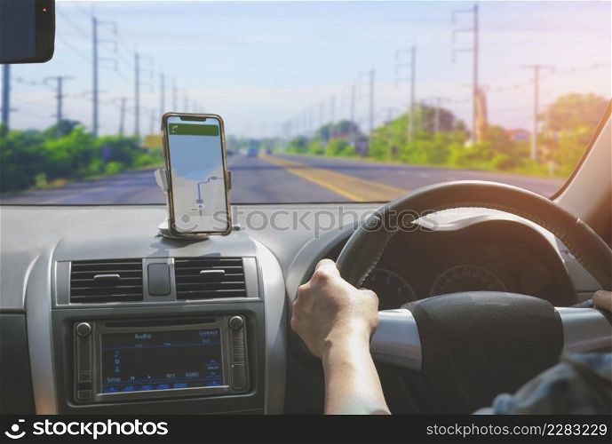 Car driver using smartphone with GPS map navigation application while driving on highway, view from inside car