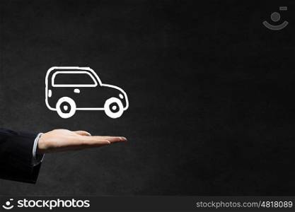 Car ensurance. Hand of businessman with car against gray background