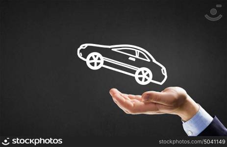 Car ensurance. Hand of businessman with car against gray background