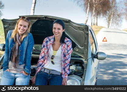 Car failure two young women waiting for help road assistance