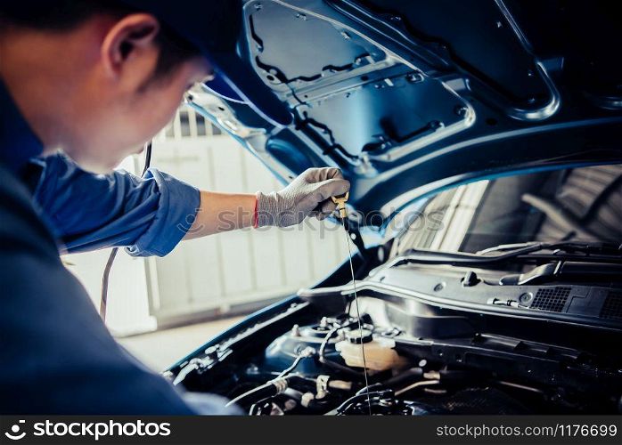 Car mechanic holding checking gear oil to maintenance vehicle by customer claim order in auto repair shop garage. Engine repair service. People occupation and business job. Automobile technician