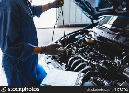 Car mechanic holding checking gear oil to maintenance vehicle by customer claim order in auto repair shop garage. Engine repair service. People occupation and business job. Automobile technician