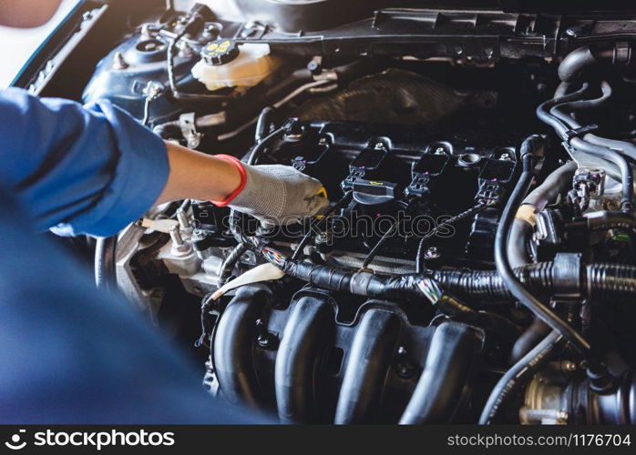 Car mechanic holding checking gear oil to maintenance vehicle by customer claim order in auto repair shop garage. Engine repair service. People occupation and business job. Automobile technician