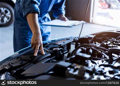 Car mechanic holding clipboard and checking to maintenance vehicle by customer claim order in auto repair shop garage. Engine repair service. People occupation and business job. Automobile technician