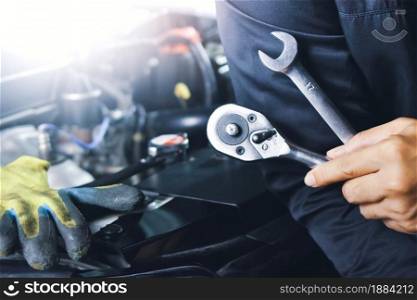 Car mechanic holding wrench in the auto repair garage