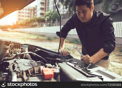 Car mechanic is holding a wrench ready to check the engine and maintenance.