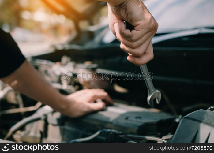 Car mechanic is holding a wrench ready to check the engine and maintenance.