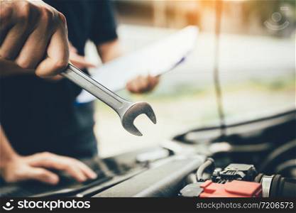 Car mechanic is holding a wrench ready to check the engine and maintenance.