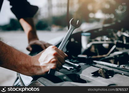 Car mechanic is holding a wrench ready to check the engine and maintenance.