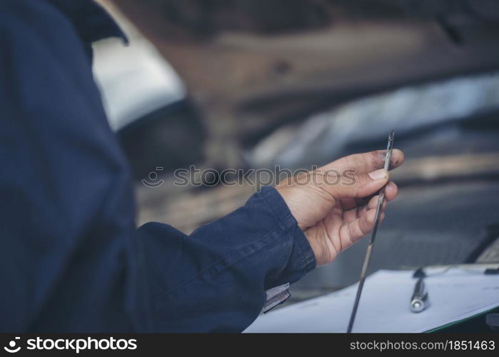 Car Mechanic man hand checking dipstick engine oil car mechanical on site service. Close up hand man check engine oil level Locate dipstick, wipe clean, check dipstick level before fill up engine oil