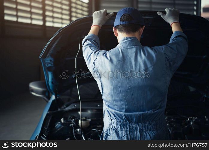 Car mechanic opening car hood for internal checking to maintenance vehicle by customer claim order in auto repair shop garage. Engine repair service. People occupation and job. Automobile technician
