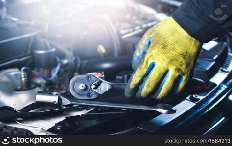 Car mechanic picking up socket wrench and tools on the car body in the repair garage