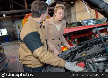 car mechanic point out towards the customer the car problem