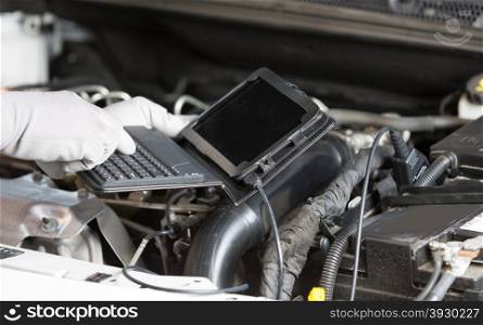 Car mechanic with a tablet making a diagnosis engine