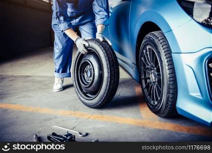 Car mechanics changing tire at auto repair shop garage. Transportation and Business working people concept. Automobile technician maintenance vehicle by customer claim order. Wheel repair service