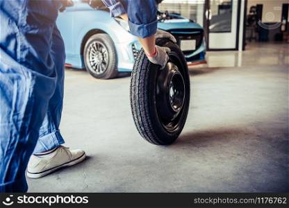 Car mechanics changing tire at auto repair shop garage. Transportation and Business working people concept. Automobile technician maintenance vehicle by customer claim order. Wheel repair service