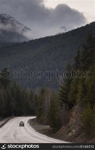 Car moving on road through coastal forest, BC Coast, Coast Mountains, Squamish, British Columbia, Canada