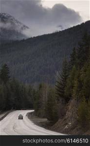 Car moving on road through coastal forest, BC Coast, Coast Mountains, Squamish, British Columbia, Canada