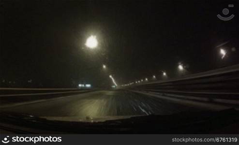 Car moving on the night road through snowstorm