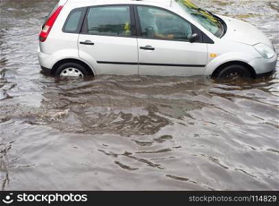 Car on a road flooded by water in a rain. Traffic problem.