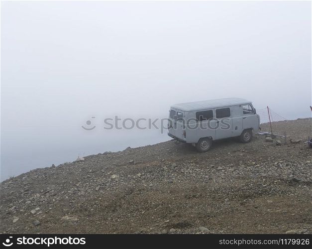 Car on the brink of an abyss in the fog of the clouds. Caucasus mountains